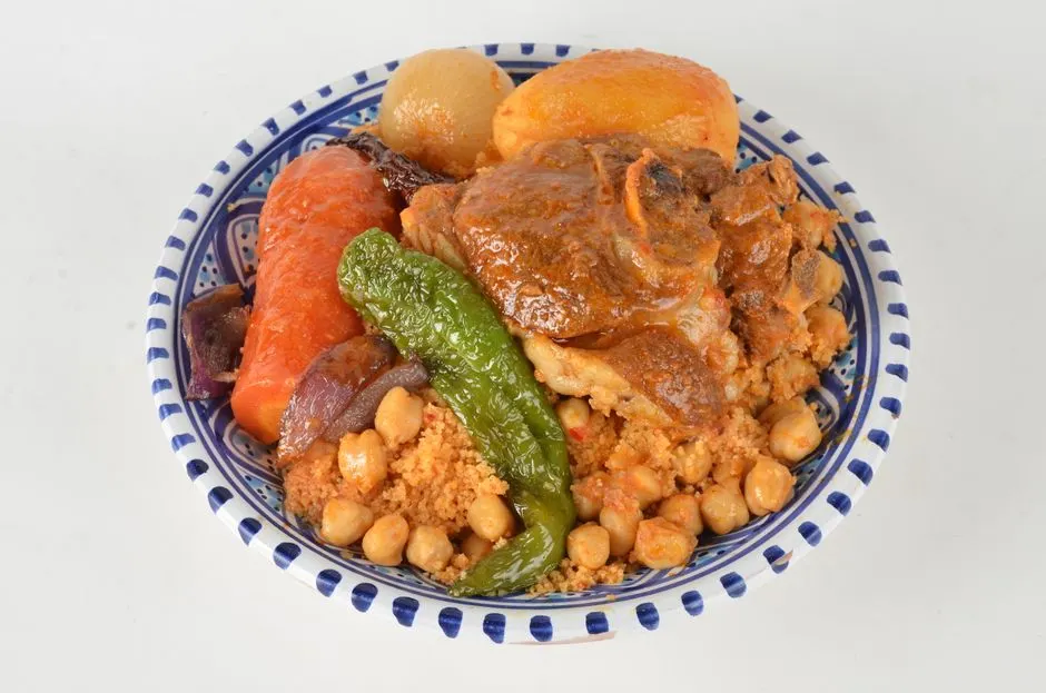 Tajine de couscous avec légumes colorés et bouillon fumant sur une table de fête